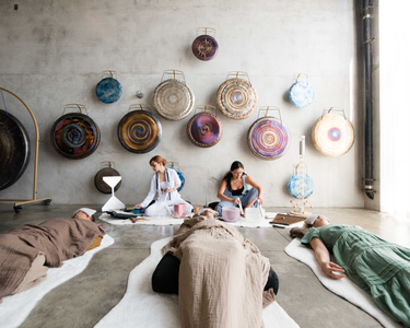Sound healing bath experience, where participants are deeply relaxed, lying comfortably as soothing vibrations from crystal singing bowls fill the space, promoting calm, balance, and inner peace.