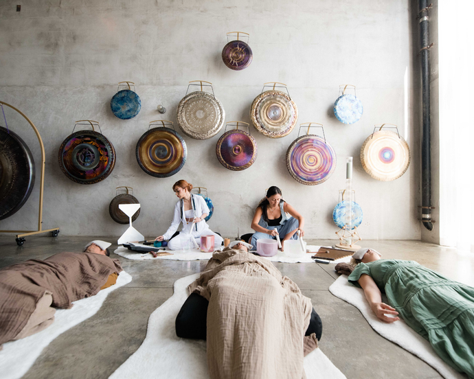 Sound healing bath experience, where participants are deeply relaxed, lying comfortably as soothing vibrations from crystal singing bowls fill the space, promoting calm, balance, and inner peace.