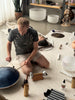 Diverse collection of sound healing instruments, including crystal singing bowls, tuning forks, and wave drums, displayed in an inviting studio setting, showcasing the variety available for exploration and use.